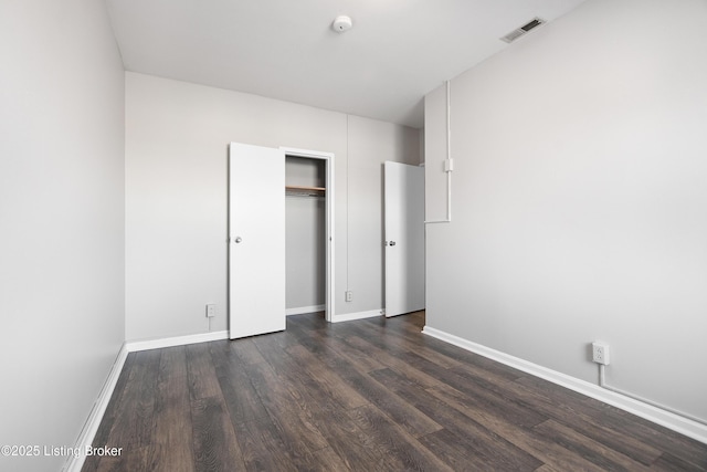 unfurnished bedroom featuring baseboards, a closet, visible vents, and dark wood-type flooring