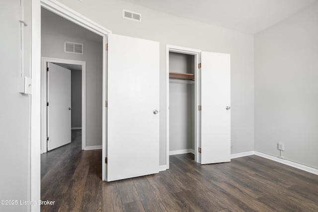 unfurnished bedroom with baseboards, a closet, visible vents, and dark wood-type flooring
