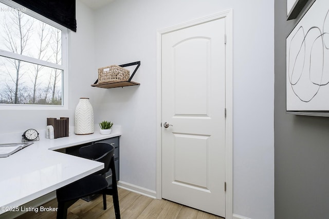 home office with light wood-type flooring and baseboards