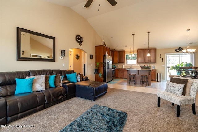 living room featuring light carpet, high vaulted ceiling, plenty of natural light, and arched walkways