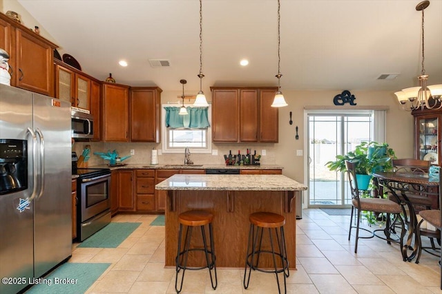 kitchen featuring a sink, visible vents, appliances with stainless steel finishes, light stone countertops, and brown cabinetry