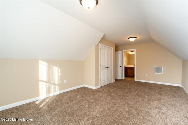 additional living space with carpet, visible vents, vaulted ceiling, and baseboards