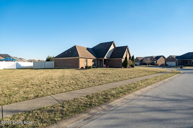 view of front of house with a front lawn, a residential view, fence, and brick siding