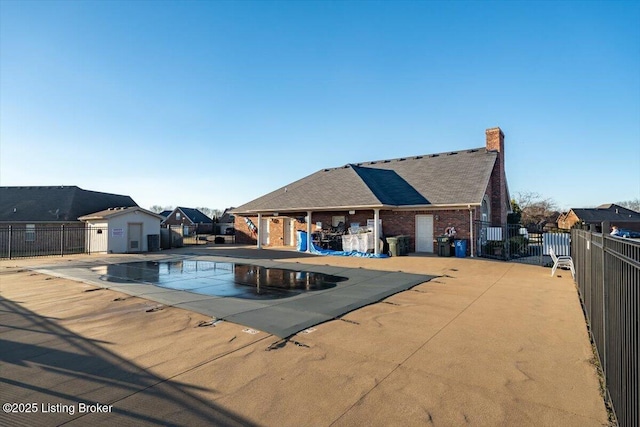 community pool with an outbuilding, a patio, and fence