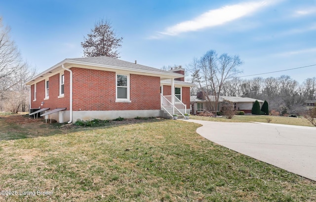 view of front of house featuring brick siding, a chimney, concrete driveway, and a front lawn