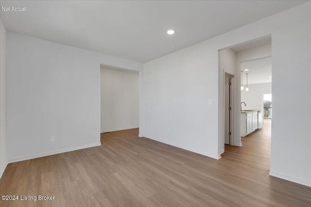 unfurnished room with recessed lighting, a sink, baseboards, and wood finished floors