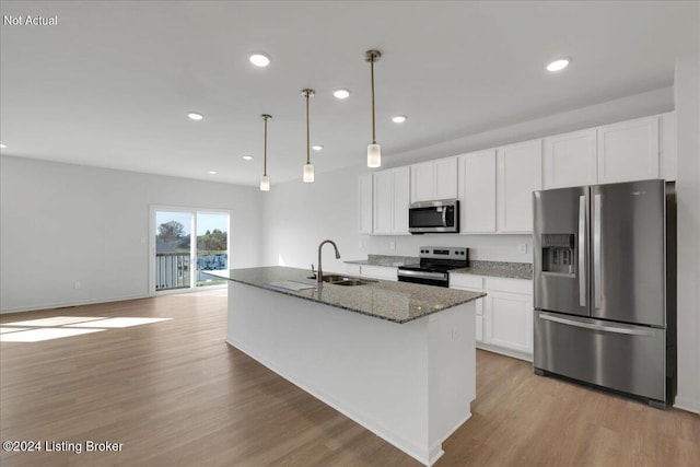 kitchen featuring stainless steel appliances, light wood-style floors, white cabinetry, a sink, and dark stone counters