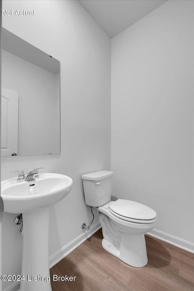 bathroom featuring toilet, a sink, baseboards, and wood finished floors