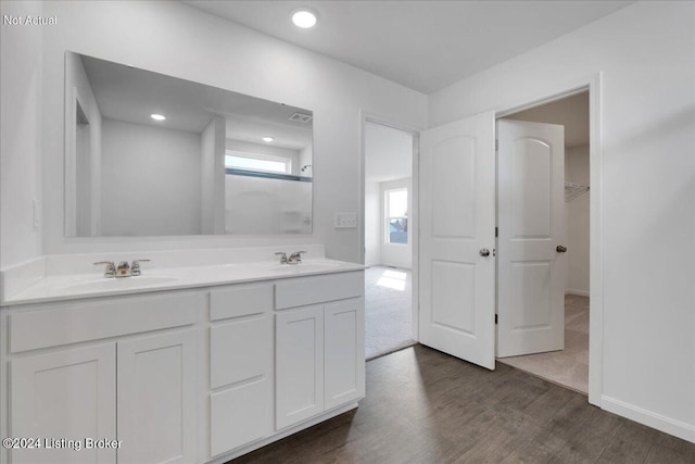 bathroom with double vanity, visible vents, a sink, and wood finished floors