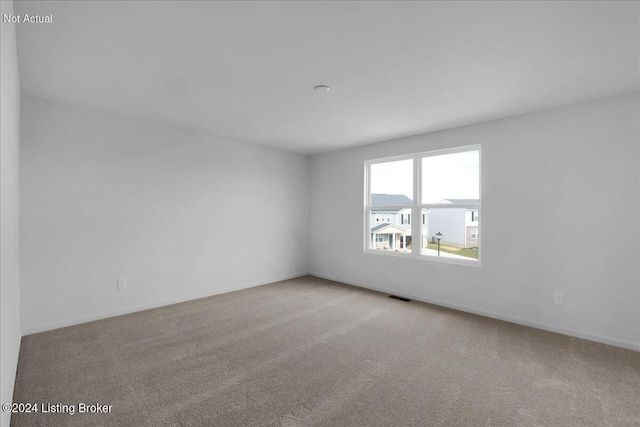 empty room with carpet flooring, visible vents, and baseboards