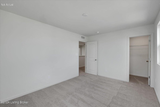 unfurnished bedroom with visible vents, baseboards, a spacious closet, a closet, and carpet