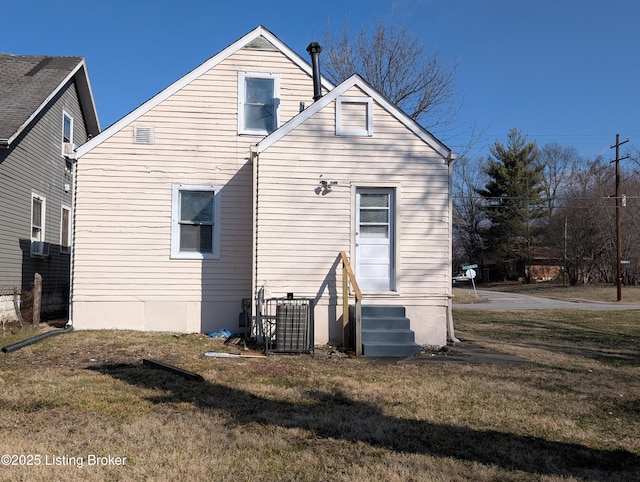 back of property with entry steps, cooling unit, and a yard