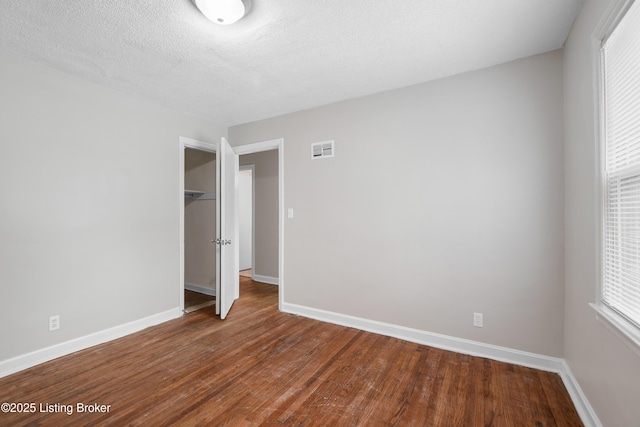 unfurnished bedroom with wood finished floors, visible vents, and baseboards