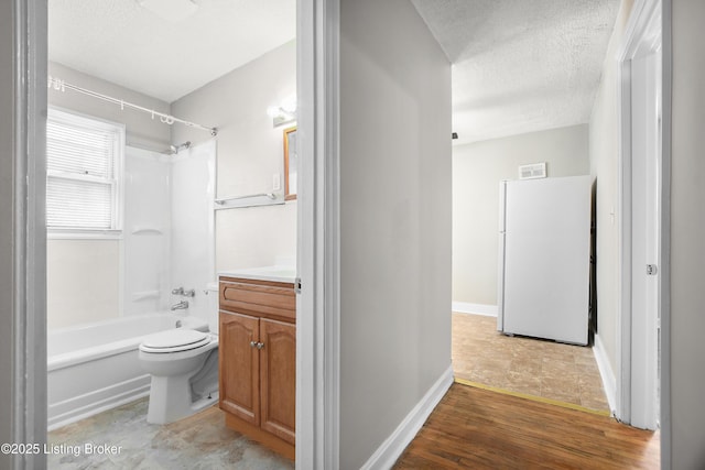 bathroom with a textured ceiling, toilet, vanity, baseboards, and tub / shower combination