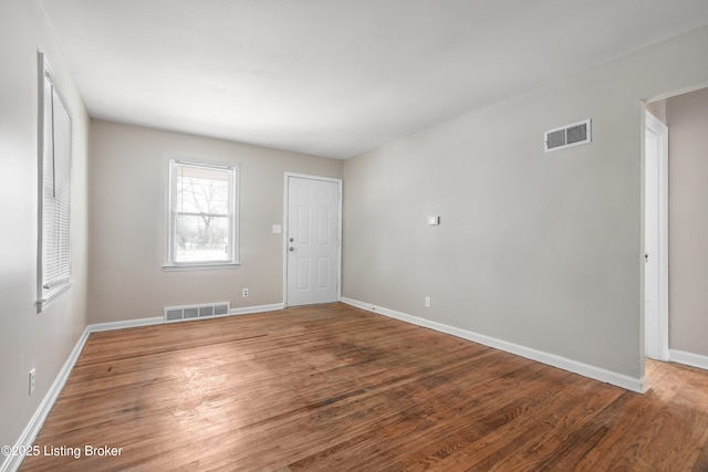 spare room with visible vents, baseboards, and wood finished floors