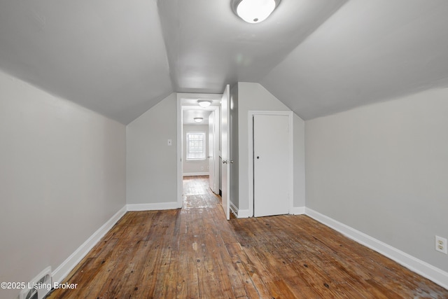 bonus room featuring wood-type flooring, visible vents, vaulted ceiling, and baseboards