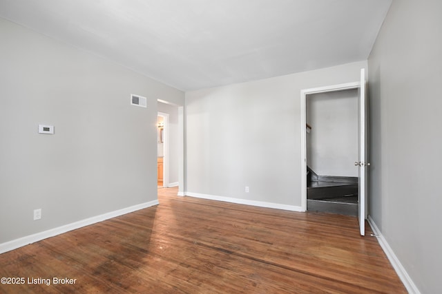 empty room featuring visible vents, baseboards, and wood finished floors