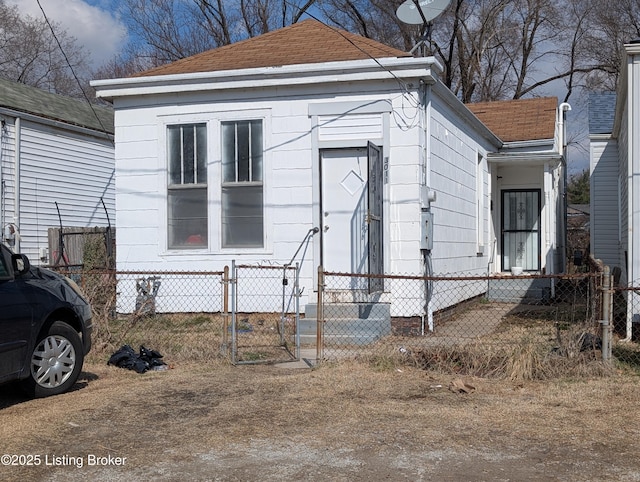 view of front of property with a fenced front yard, a gate, and roof with shingles