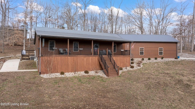 view of front of property featuring covered porch, metal roof, and stairs