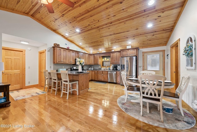 kitchen featuring a peninsula, appliances with stainless steel finishes, light wood-type flooring, and a breakfast bar