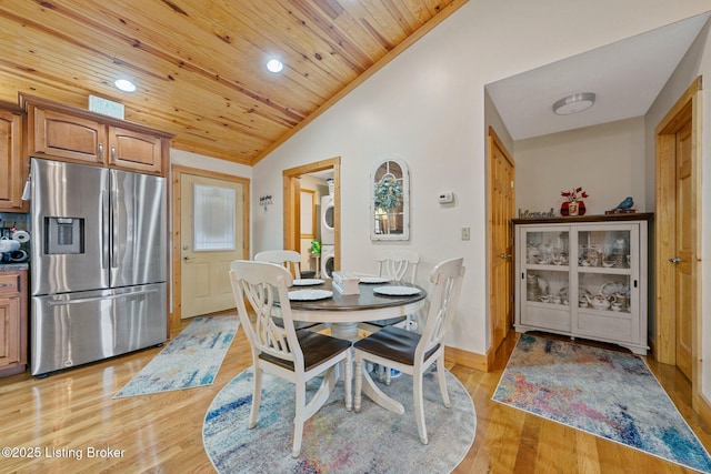 dining area featuring wooden ceiling, vaulted ceiling, light wood finished floors, and stacked washer and clothes dryer