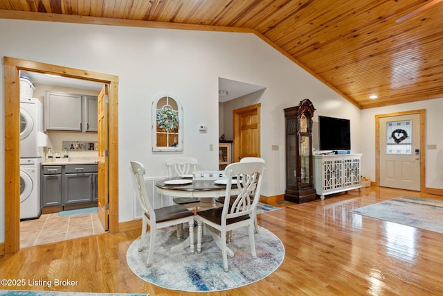 dining space with wooden ceiling, stacked washer / dryer, baseboards, vaulted ceiling, and light wood finished floors