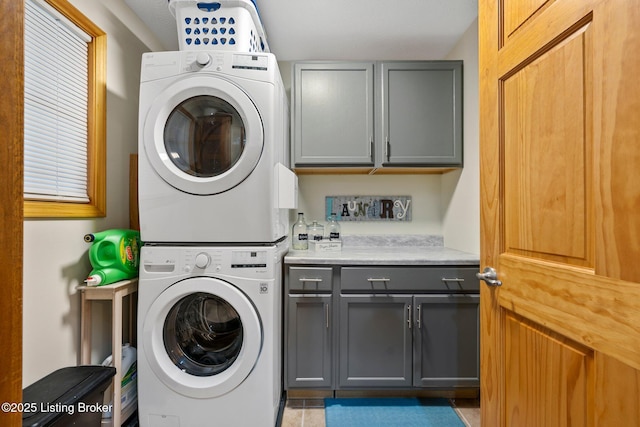 clothes washing area with stacked washer / dryer and cabinet space