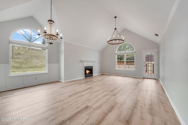 unfurnished living room featuring high vaulted ceiling, light wood finished floors, visible vents, a chandelier, and a lit fireplace