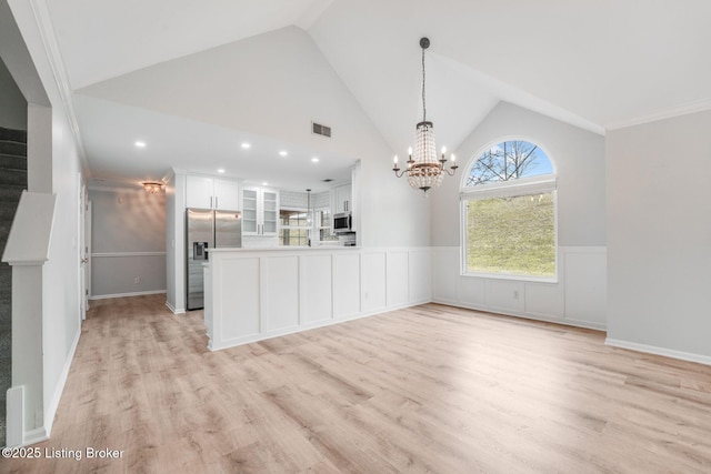 interior space with visible vents, wainscoting, stairway, light wood-type flooring, and a chandelier