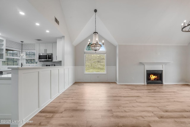 interior space with light wood-style floors, visible vents, a chandelier, and stainless steel microwave