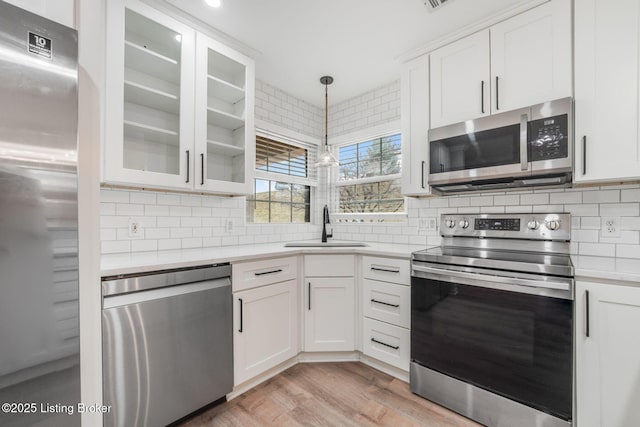 kitchen with appliances with stainless steel finishes, light countertops, a sink, and decorative backsplash