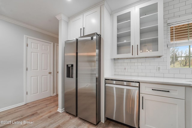 kitchen with crown molding, stainless steel appliances, tasteful backsplash, light countertops, and white cabinets