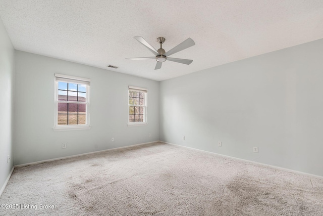 unfurnished room featuring carpet floors, visible vents, ceiling fan, a textured ceiling, and baseboards