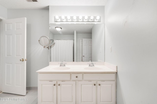 bathroom featuring double vanity, a textured ceiling, and a sink