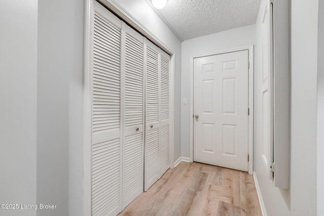 corridor with a textured ceiling and light wood-style floors