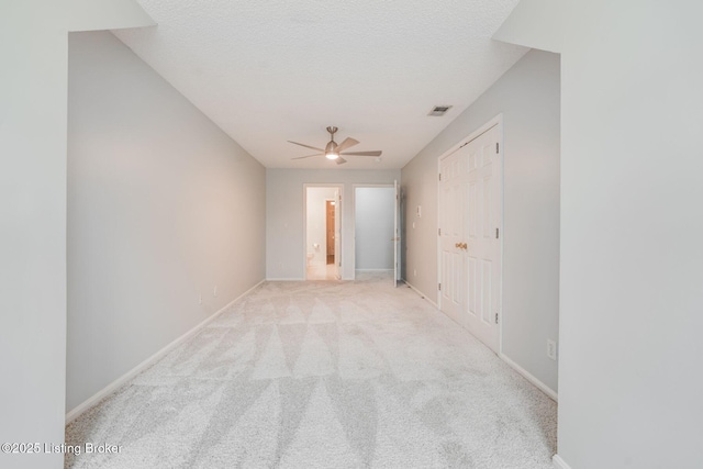 empty room featuring carpet floors, visible vents, a textured ceiling, and baseboards