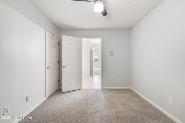 carpeted spare room with a ceiling fan, a textured ceiling, and baseboards