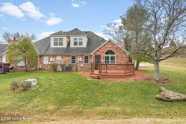 view of front of home featuring roof with shingles, a front yard, a deck, and brick siding