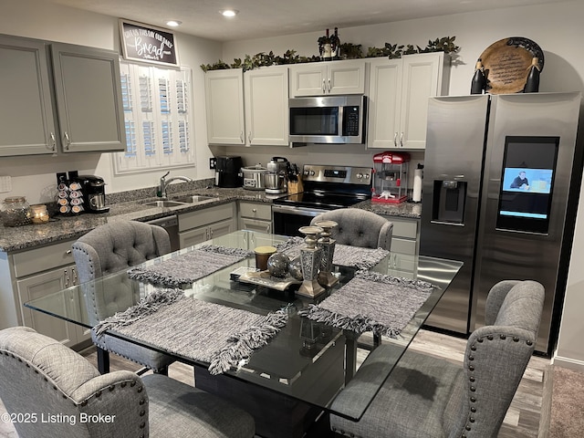 kitchen with appliances with stainless steel finishes, stone counters, white cabinetry, a sink, and recessed lighting