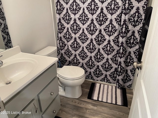 full bath featuring vanity, curtained shower, wood finished floors, and toilet