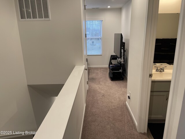 corridor featuring recessed lighting, carpet floors, a sink, visible vents, and baseboards