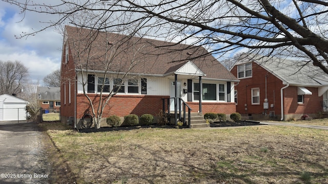 view of front of house with brick siding, roof with shingles, and an outdoor structure