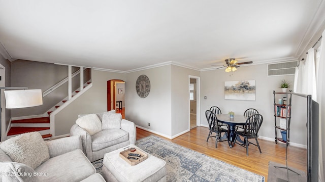 living room with arched walkways, wood finished floors, visible vents, ornamental molding, and stairway