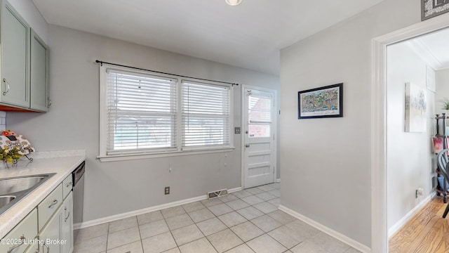 kitchen with gray cabinets, visible vents, light countertops, stainless steel dishwasher, and baseboards