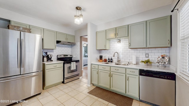 kitchen with under cabinet range hood, green cabinets, stainless steel appliances, and a sink