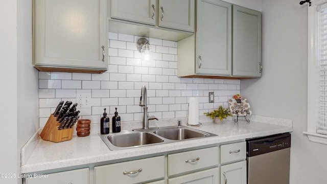 kitchen with light countertops, stainless steel dishwasher, backsplash, and a sink