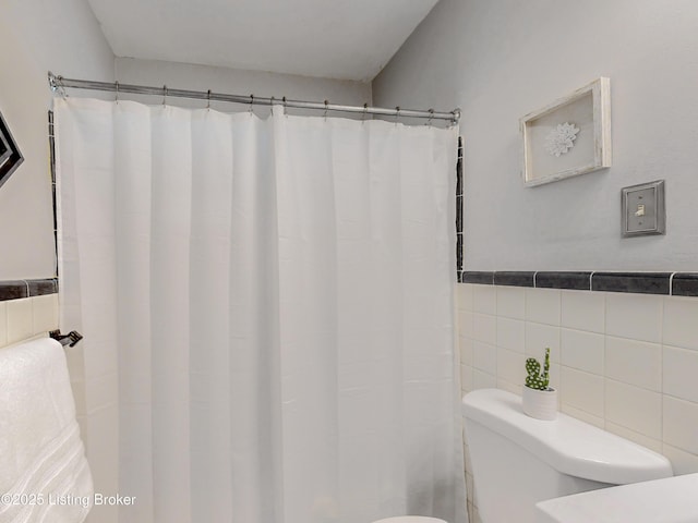 bathroom with toilet, tile walls, and a shower with shower curtain