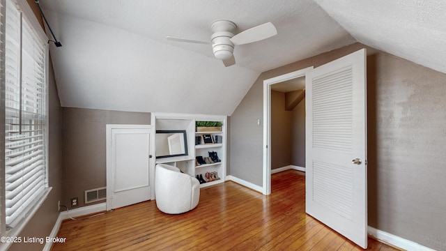 additional living space featuring lofted ceiling, wood-type flooring, visible vents, and baseboards