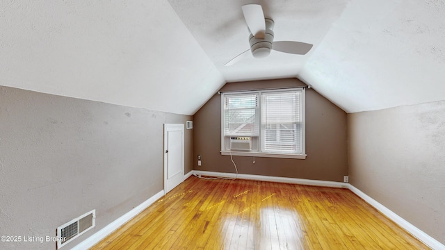 additional living space with cooling unit, visible vents, baseboards, vaulted ceiling, and wood-type flooring