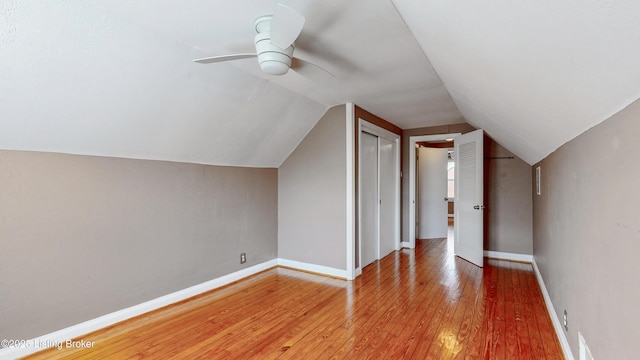 additional living space with vaulted ceiling, light wood-style flooring, baseboards, and ceiling fan